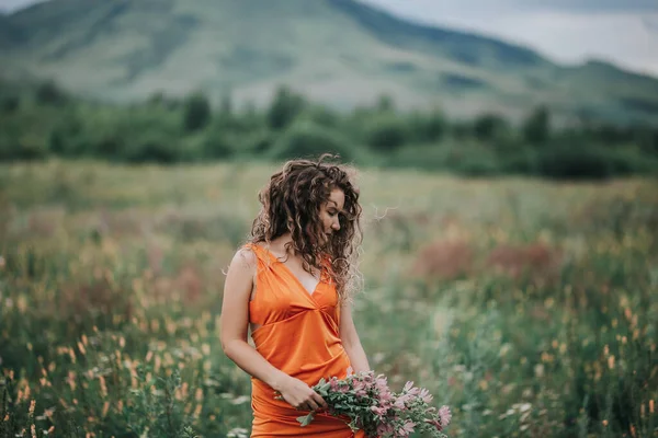 Elinde Bir Buket Çiçekle Turuncu Elbiseli Bir Kız Çimlerin Dağların — Stok fotoğraf