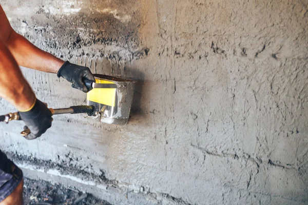 Homme plâtrant un mur avec du mortier à l'aide d'un seau trémie — Photo
