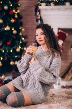 Süveter giymiş güzel seksi bir kız elinde bir bardak şampanya tutuyor, Noel gecesi..