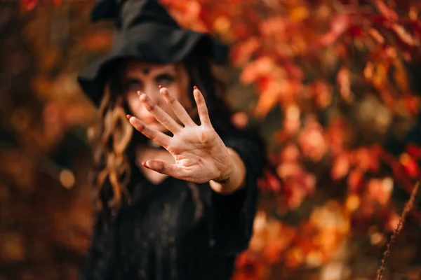 Close-up face of woman wearing witch hat on head for halloween Foco selecionado na mão, bruxa desfocada — Fotografia de Stock