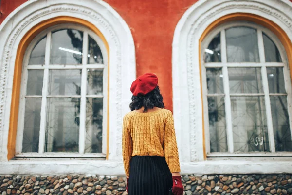 Donna in maglione giallo e cappello rosso sullo sfondo di un edificio con grandi finestre Focus selezionato — Foto Stock