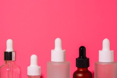 Sıraya dizilmiş şişeler pembe arka plana karşı. Cilt bakımı ve güzellik malzemeleri. Yüksek kalite fotoğraf