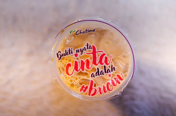 Chatime franchise 'den Brown Sugar Taze Süt Çayı' nın resmedilmiş bir başyazısı. Bahasa Endonezya 'da yazılmış ifadenin üst görüşü ile birlikte..