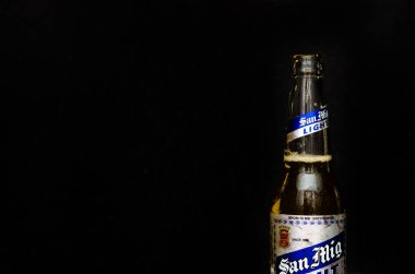 Siyah mermer arka planda gümüş ve mavi etiketli San Miguel Light birasının yakın görüntüsü.