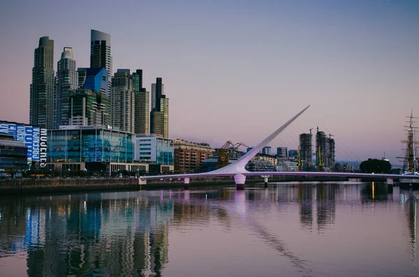 Buenos Aires, Arjantin - 6 Eylül 2018: Günbatımında Rio de la Plata üzerinde Puente de la Mujer isimli ikonik köprü ile Buenos Aires 'in iş bölgesi.
