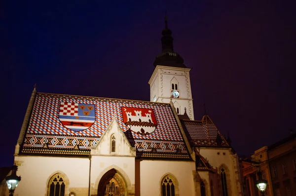 Hırvatistan 'ın Zagreb kentindeki St. Mark Kilisesi, arka plandaki koyu mavi ve bulutlu akşamın aksine aydınlandı.