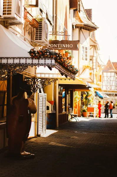 Çiçeklerle süslenmiş dükkan girişlerinin dikey görüntüsü ve öğleden sonra Brezilya 'daki Vila Germanica, Blumenau' daki Pontinho mağazasının tabelası..