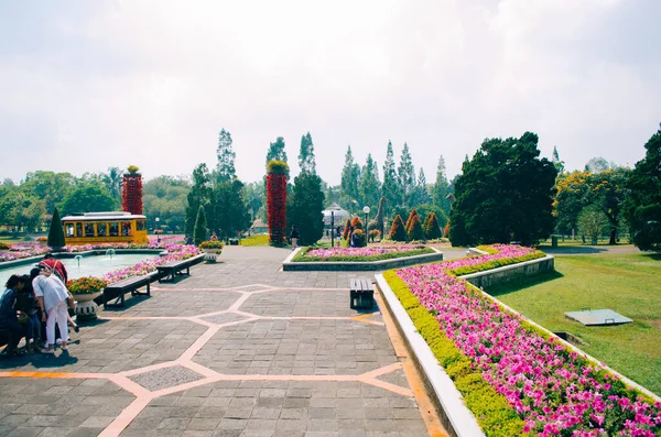 Bogor, Endonezya - Bulutlu bir öğleden sonra Taman Bunga Nusantara adlı çiçek temalı parkın manzarası, neredeyse boş bir patika manzarası, uzaktan sarı bir tramvay ve bir grup bayan arkadaş sol köşede toplandı.