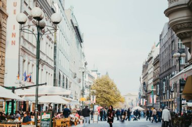 Prag, Çekoslovakya - Bir kadın kışlık giysiler giyiyor ve kalabalık bir meydanda turist ve yerel halkla yan yana bakıyor.