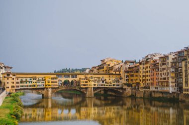Roma, İtalya - Ponte Vecchio ve Arno nehrinin panoramik tarafı bulutlu bir öğleden sonra sularındaki binaları yansıtıyor.