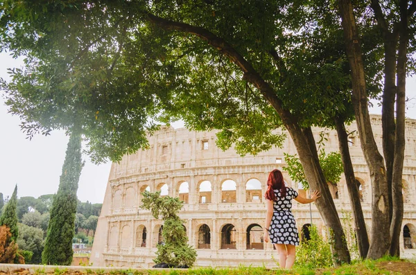Roma, İtalya - 20 'li yaşlarda kızıl saçlı genç Brezilyalı bir kadın öğleden sonra bir parkta çekilen Colosseum' u araştırıyor..
