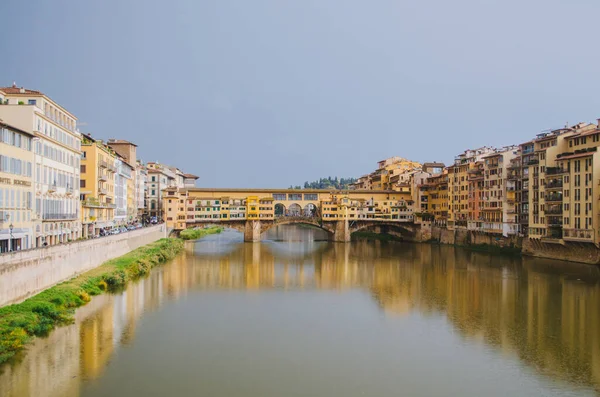 Roma, İtalya - Ponte Vecchio ve Arno nehrinin bulutlu bir öğleden sonra sularındaki binaları yansıtan panoramik manzarası.