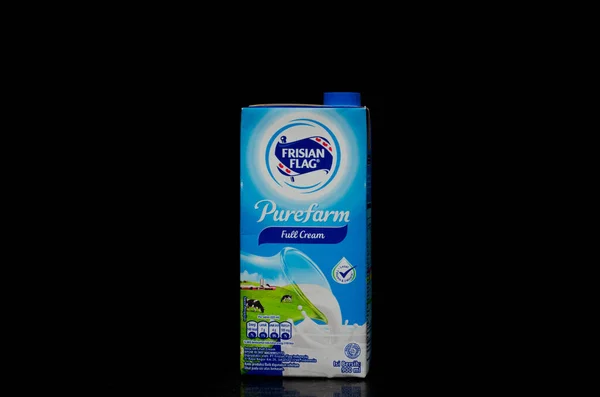 Frisian Flag markasından bir litre kremalı süt kutusunun ön görüntüsü siyah arka planda izole edilmiş..