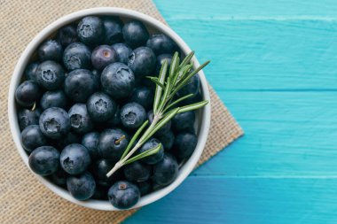 Taze yabanmersinleri beyaz kasede mavi ahşap masadaki en üstte arka plan için fotokopi alanı olan taze yabanmersini. Yabanmersini antioksidan yiyecek ve C vitamini sağlıklı ve lezzetli meyve konseptidir..