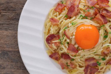 Pastırma, peynir, yumurta sarısı ve maydanozlu spagetti carbonara 'yı kapayın. En üstteki tahta masanın üzerinde fotokopi alanı var. İtalyan geleneksel ev yemeği öğle veya akşam yemeği çok kremalı ve lezzetli.