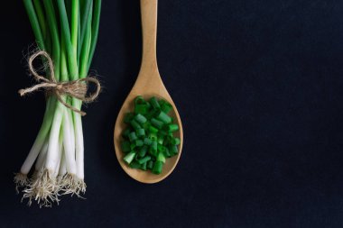 Siyah granit masada taze taze taze soğan. Doğranmış Callion 'a yakın dur ya da tepedeki düz yerde taze soğan var. Taze soğanı pişirmeye hazırlayın. Arkaplan veya duvar kağıdı için gıda ve sebze kavramı.