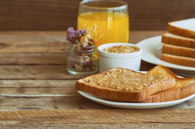 Ev yapımı fıstık ezmeli tost ekmeği portakal suyuyla servis edilir. Kahvaltı için ahşap masada fıstık ezmeli ev yapımı tost ekmeği. Ev yapımı fıstık ezmeli lezzetli tost ekmeği..