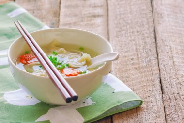 Tahta masaya konmuş peçete üzerine beyaz kâse içinde ev yapımı kıymalı domuz çorbası. Kahvaltıda, öğle yemeğinde ya da akşam yemeğinde leziz wonton çorbası. Wonton ya da hamur köftesi her zaman popüler Çin yemeğidir..