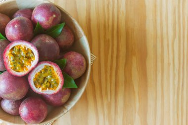 Ahşap kasedeki taze tutku meyvesi ahşap masa üzerinde düz zemin veya arka plan veya duvar kağıdı için fotokopi alanı ile yatıyordu. Olgun tutku meyvesi çok lezzetli ve ekşi. Tutku meyvesi tropikal meyvedir..