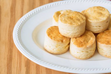 Beyaz tabakta ev yapımı tereyağlı çörek. Çörek, öğleden sonra çayı ya da kahve molası için geleneksel İngiliz pastasıdır. Ahşap masada servis edilmeye hazır lezzetli çörekler. Makro kavramı.