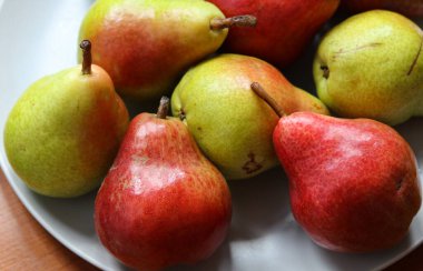 Beyaz bir tabakta olgun armutlar. Yaklaş.