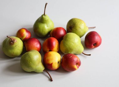 Beyaz arkaplanda olgun nektarinler ve armutlar.