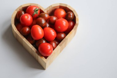 Kalp şeklinde ahşap bir kasede farklı domates türleri.