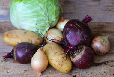 yakın plan bir masa üzerinde lahana, pancar, patates ve soğan
