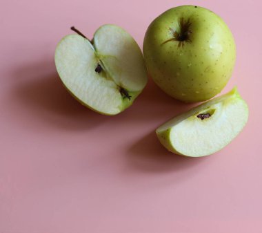 Dilimlenmiş elma ve pembe arka planda bir tane. Yakın plan.