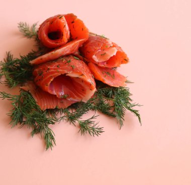 Pembe arka planda somon dilimleri ve dereotu yakın plan.