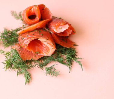 Pembe arka planda somon dilimleri ve dereotu yakın plan.