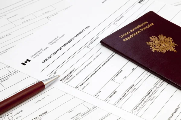 加拿大临时居民签证申请表上的圆珠笔和法国护照 — 图库照片