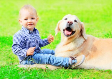 Bebek ve Golden Retriever köpek birlikte bir yaz çim üzerinde oturuyor
