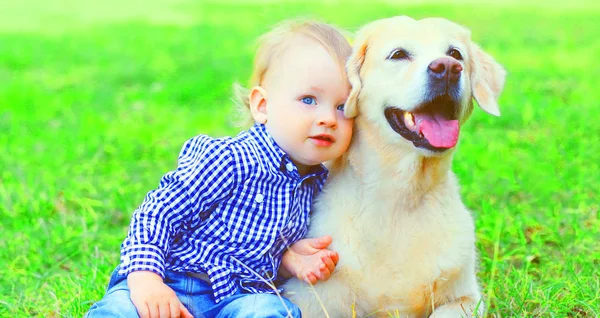 婴儿和金色猎犬狗坐在一起在草地上的夏天 — 图库照片