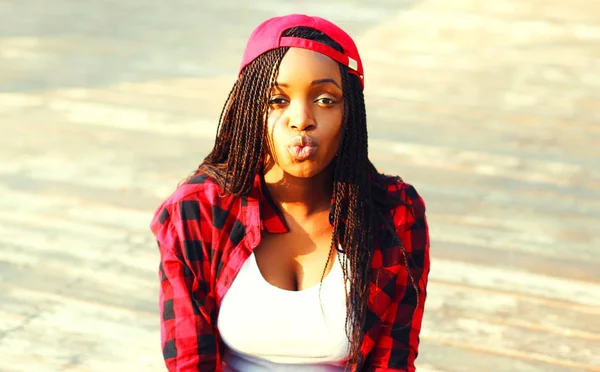 Serin kız şehirde bir kırmızı kareli gömlek ve beyzbol şapkası eğleniyor