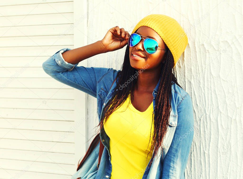 African woman with skateboard in colorful clothes and sunglasses outdoors