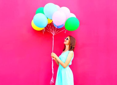 Cool kadın üzerinde pembe bir arka plan üzerinde eğleniyor bir hava renkli balonları arıyor