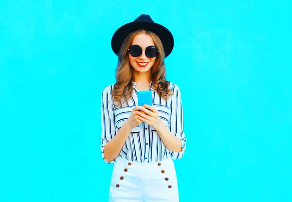 여자는 도시에 화려한 파란색 모자와 핸드백 클러치를 스마트폰 — 스톡 사진