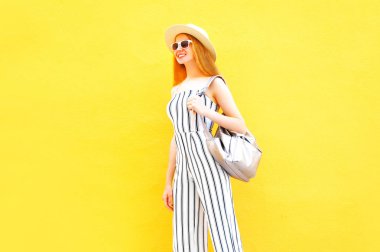 Yuvarlak şapka renkli sarı duvar arka plan üzerinde beyaz çizgili pantolon moda mutlu gülümseyen kadın