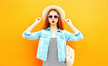 Turuncu bir arka plan üzerinde hasır şapkalı güzel kız