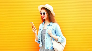 Şık kızı smartphone şehrin turuncu bir arka plan üzerinde kullanmak