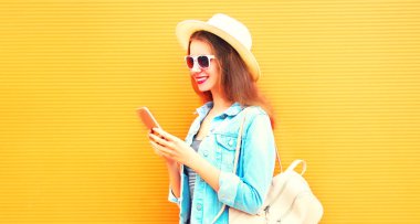 Serin kız smartphone şehrin turuncu bir arka plan üzerinde kullanıyor