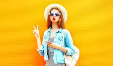 Kırmızı dudaklar ile serin mutlu kızı smartphone şehrin turuncu bir arka plan üzerinde kullanmak