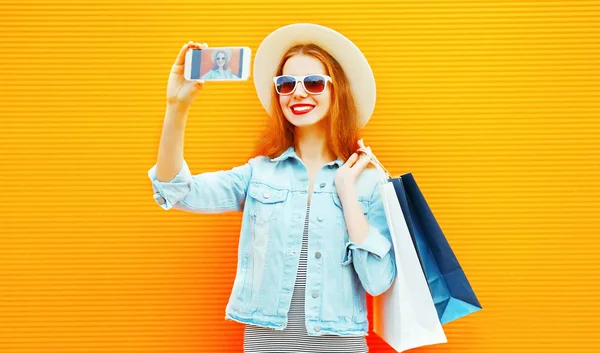 时尚快乐的女人在一个橙色背景的智能手机上拍摄图片自画像 — 图库照片