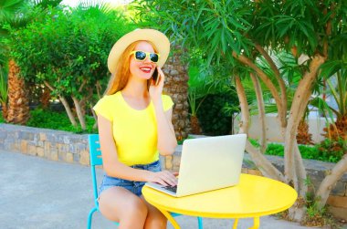 Mutlu genç gülümseyen kadın görüşmeler smartphone, bir kafeterya masada dizüstü bilgisayar