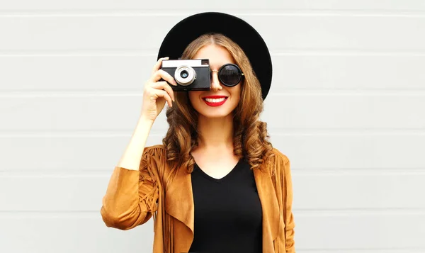 レトロなフィルム カメラ市灰色背景に屋外エレガントな帽子 茶色ジャケット 巻き毛を着てクールなファニー ガール モデル — ストック写真