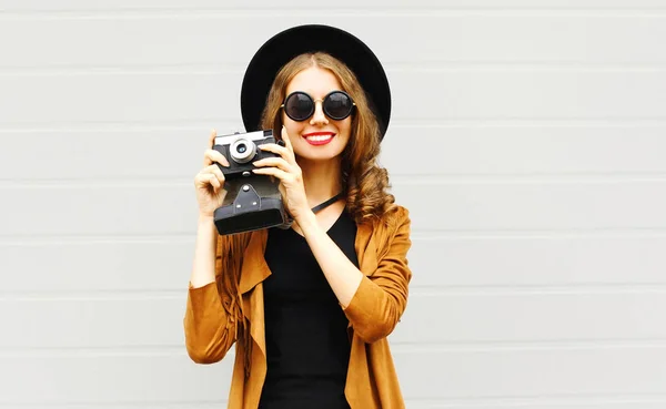 幸せな若い女性モデル都市の灰色の背景の上屋外エレガントな帽子 茶色のジャケットを着てレトロなフィルム カメラ — ストック写真