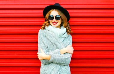 Mutlu güzel portre gülümseyen kadın kırmızı bir arka plan üzerinde bir örme giyim eşyası