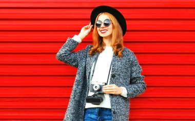 Kırmızı bir arka plan üzerinde retro kamera ile şık güzel kadın