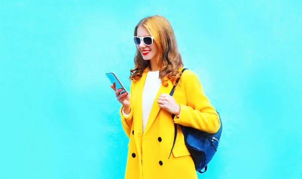 Mavi Renkli Arka Plan Üzerinde Smartphone Kullanarak Güzel Gülümseyen Kadın — Stok fotoğraf